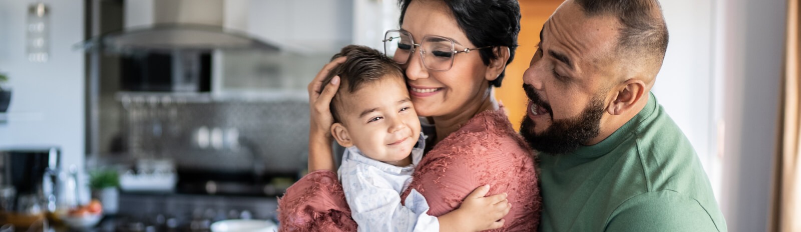 Parents holding young child in kitchen 