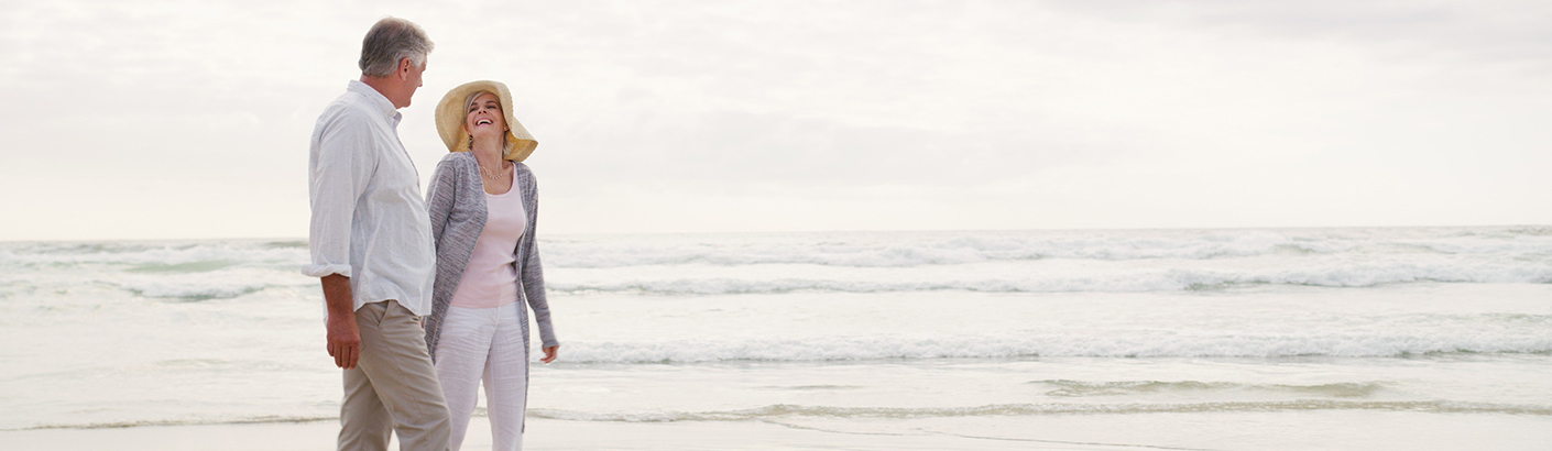 Middle aged couple on beach with calm waves coming in